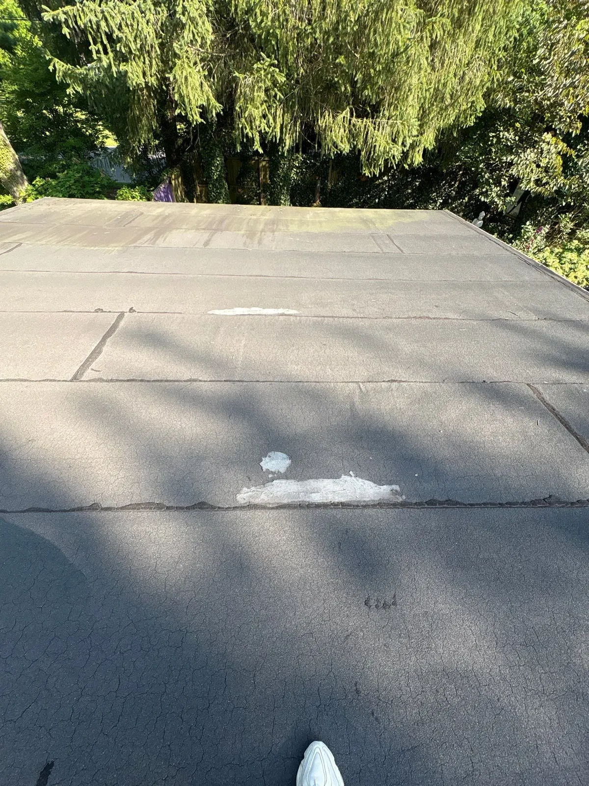 An old flat roof with a patched spot on a modern house in Princeton, NJ, before replacement.