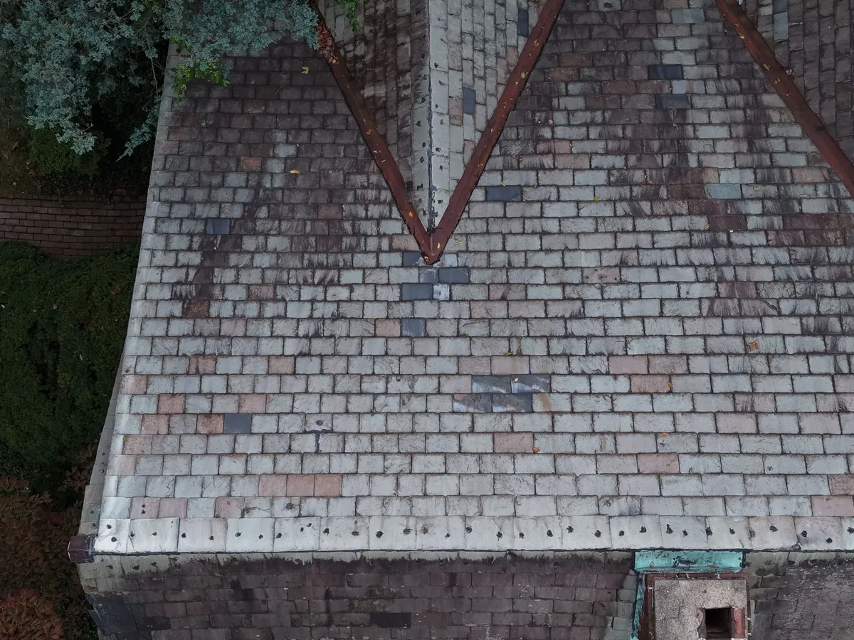 An old slate roof with a worn chimney and flashing on a Princeton, NJ house, seen from above.