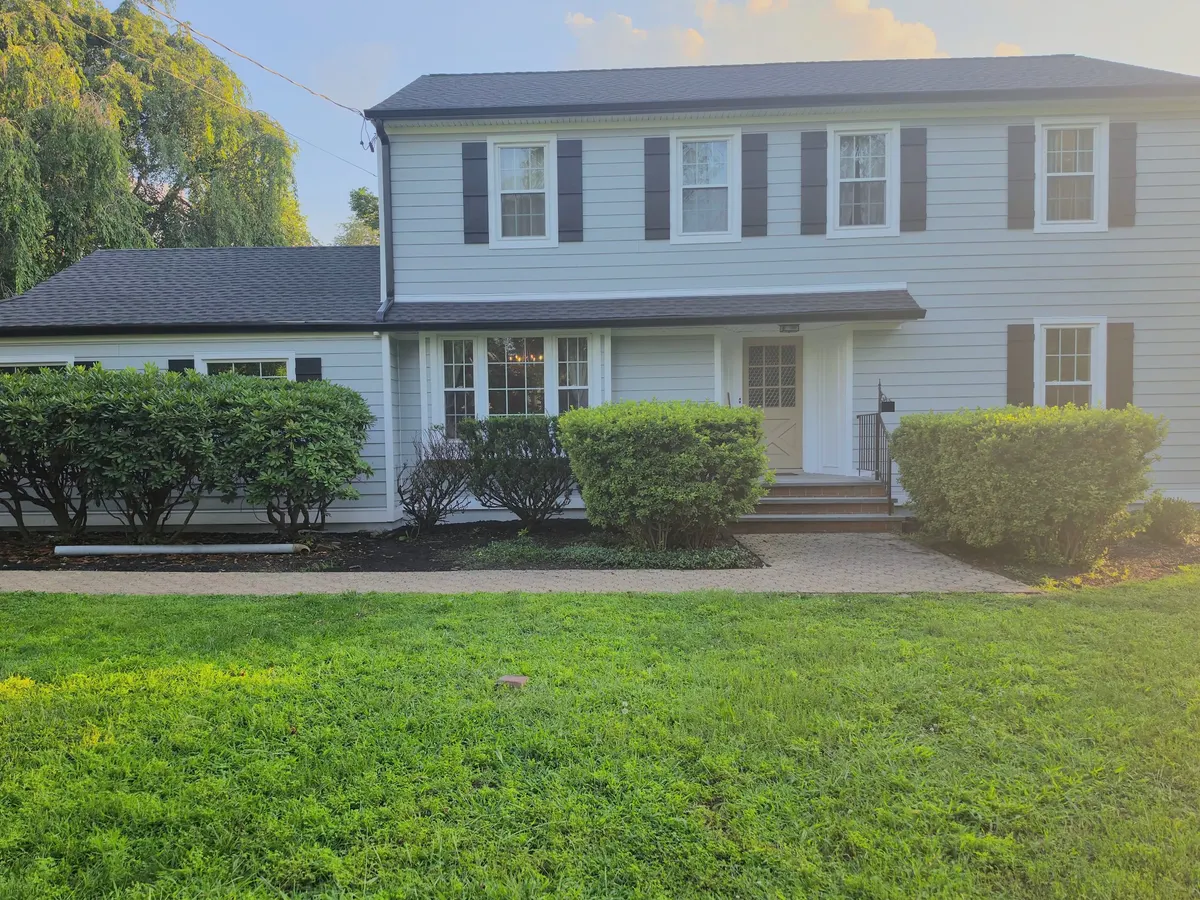 The same Princeton colonial with James Hardie siding in Light Mist and new black shutters, by Pujols Roofing.