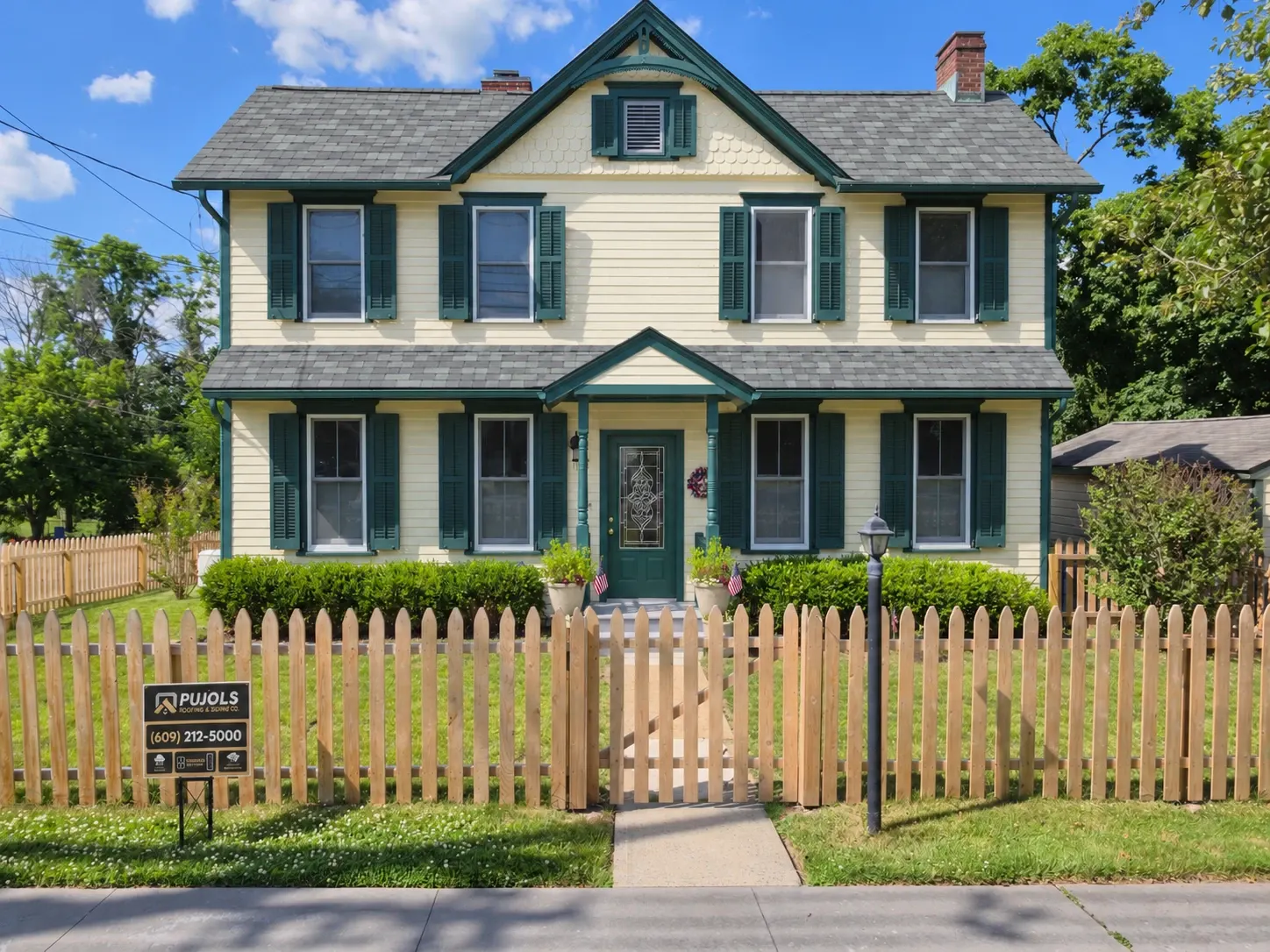 A Rocky Hill home built in 1900 after a full exterior, seen from the street: new roof, gutters and soffits, fresh cream paint with green trim and shutters, and a new front door, by Pujols Roofing.