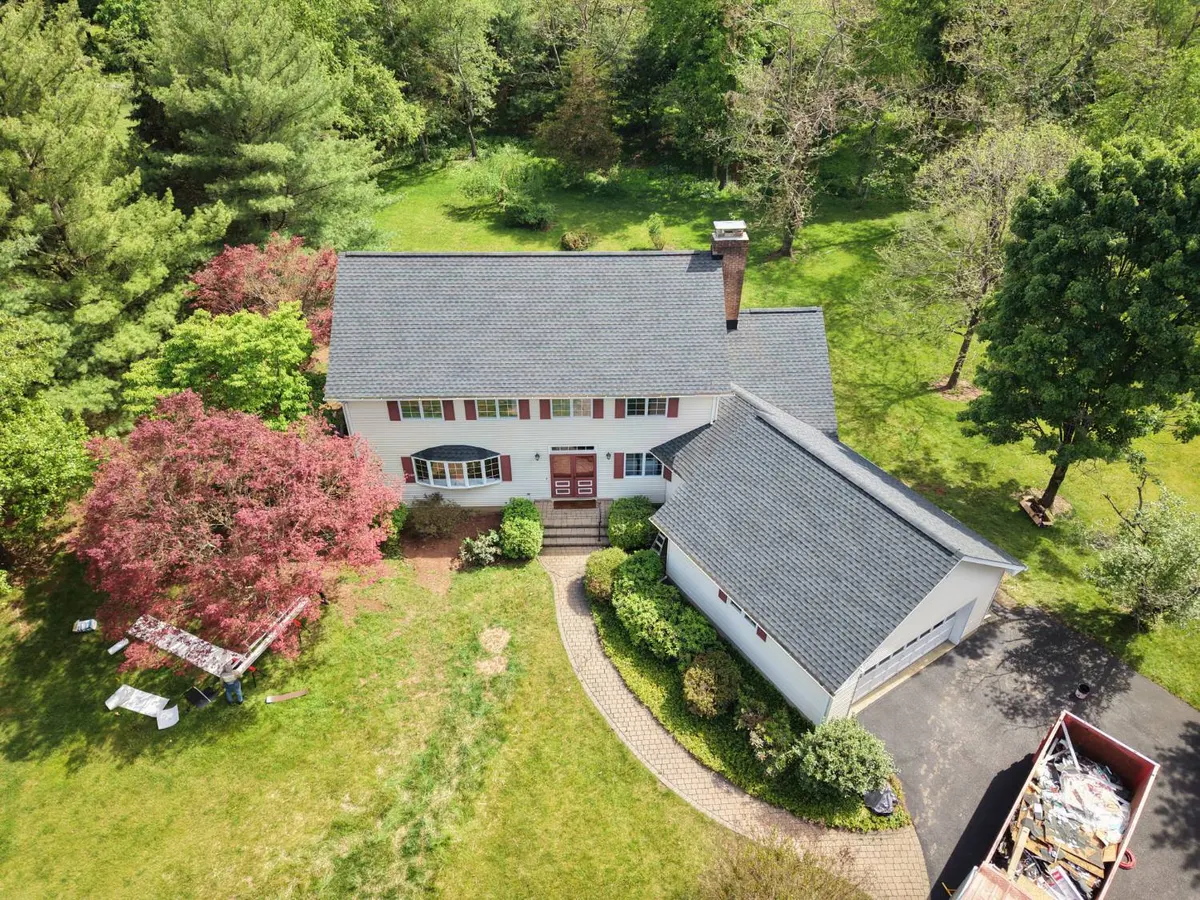 Drone view of a new GAF Ultra Timberline HDZ (UHDZ) roof in Charcoal on a white colonial with red shutters in Montgomery, NJ, a two-day roof replacement by Pujols Roofing & Siding LLC.