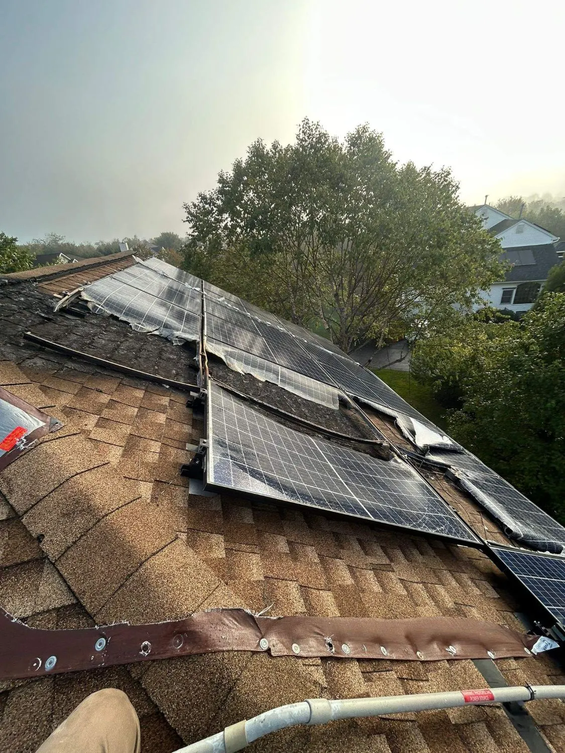 Fire-damaged solar panels and burned shingles on a roof in Franklin Township, NJ, before the roof replacement by Pujols Roofing & Siding.