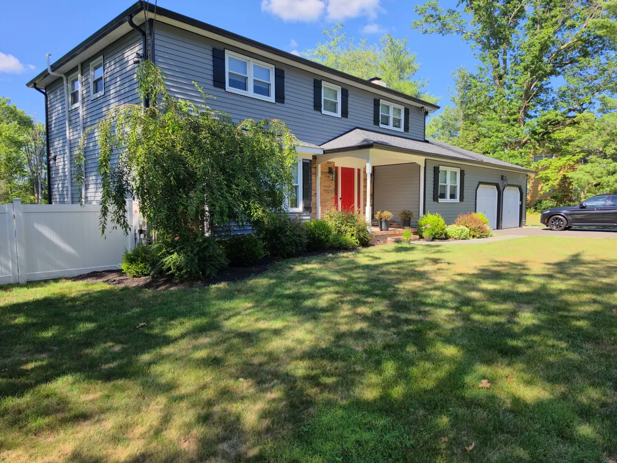 A gray two-story house on Cherry Brook Drive in Princeton, NJ with new siding and a red front door, by Pujols Roofing & Siding.