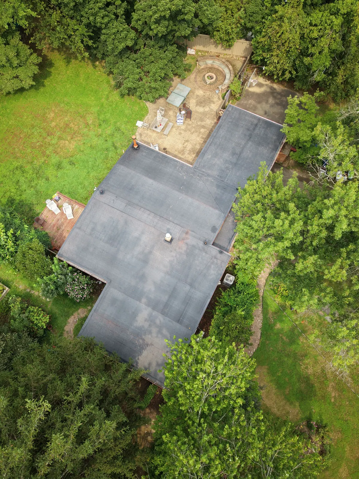 Drone view of a modern house on Deer Path in Princeton, NJ with its new flat roof, by Pujols Roofing.