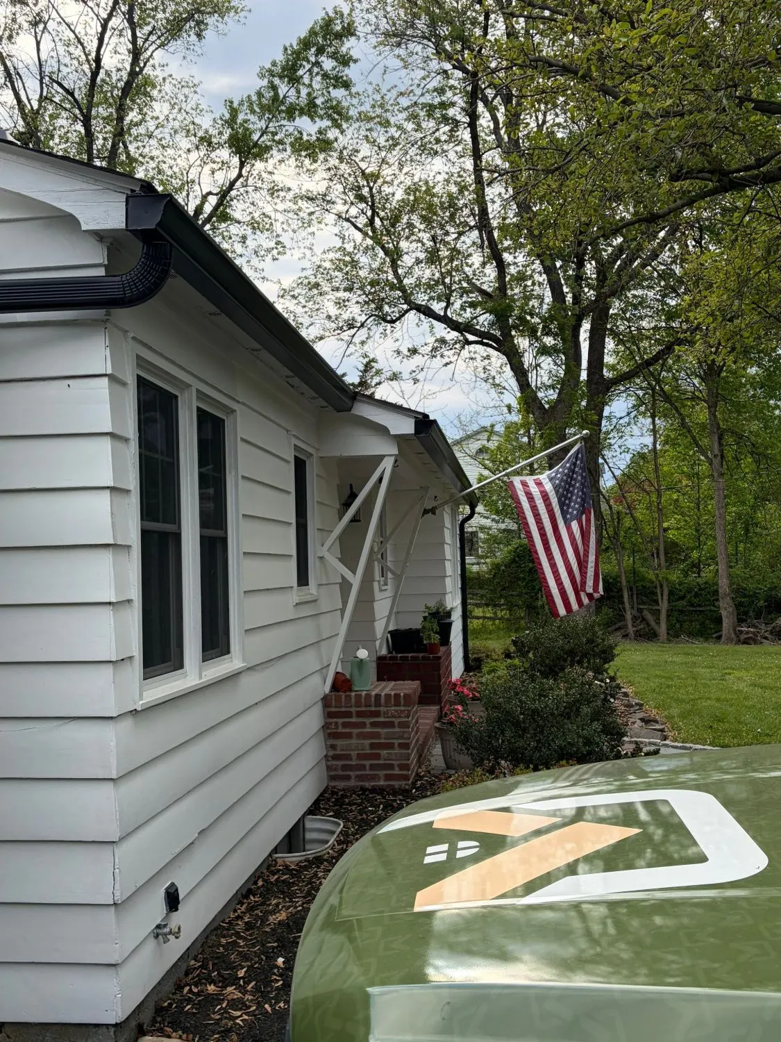 New black seamless gutters and downspout on a white house on Crescent Avenue in Rocky Hill, NJ, with the Pujols van in the driveway.