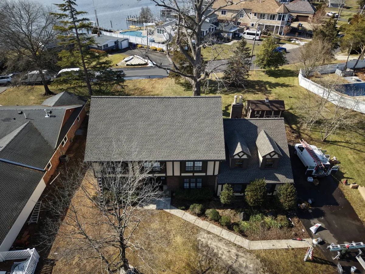 Drone view of a new GAF Timberline HDZ roof in Barkwood on an 85-year-old Tudor home near the water in Toms River, NJ, roof, trim and gutters by Pujols Roofing & Siding LLC.