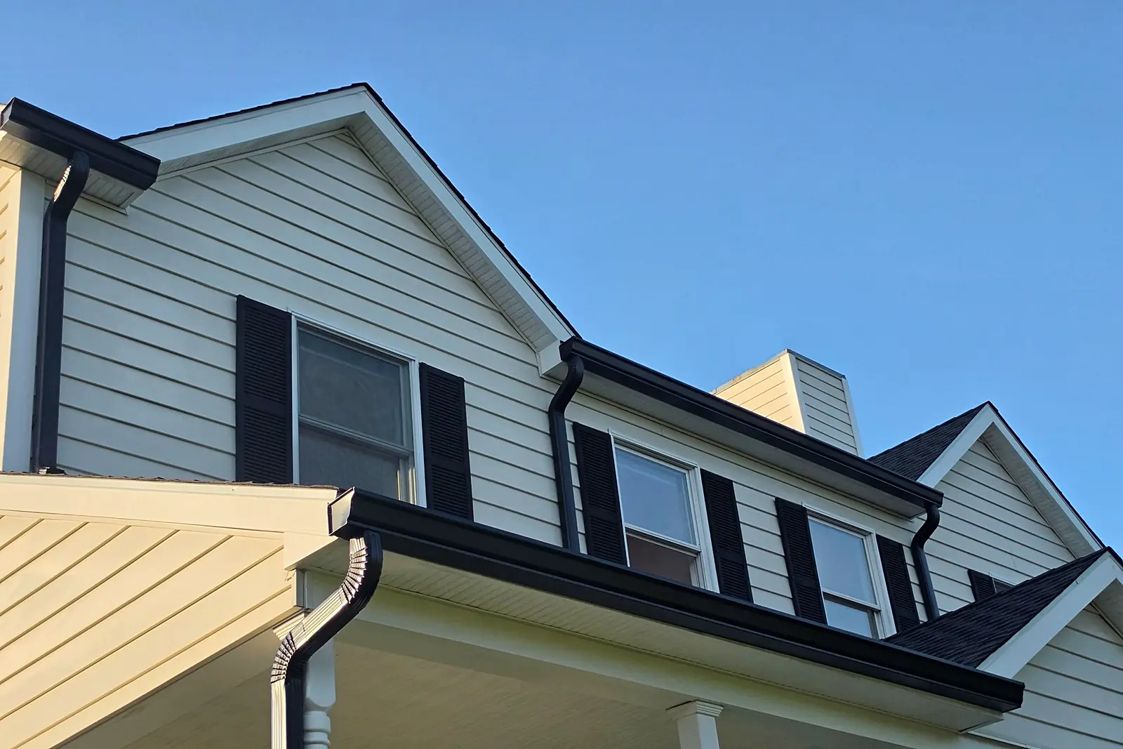 New black seamless aluminum 6-inches gutters and downspouts on a cream colonial in Skillman, NJ by Pujols Roofing & Siding LLC.